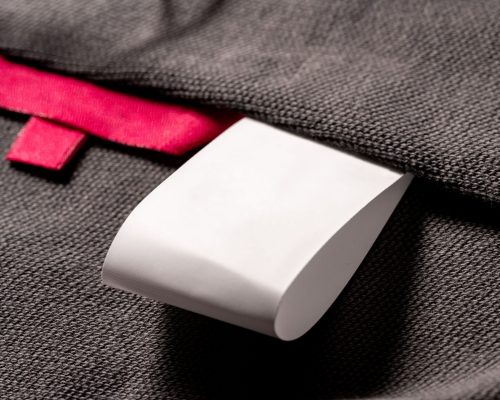 A closeup shot of a blank red fabric tag on cloth for a size label and a white tag for laundry details